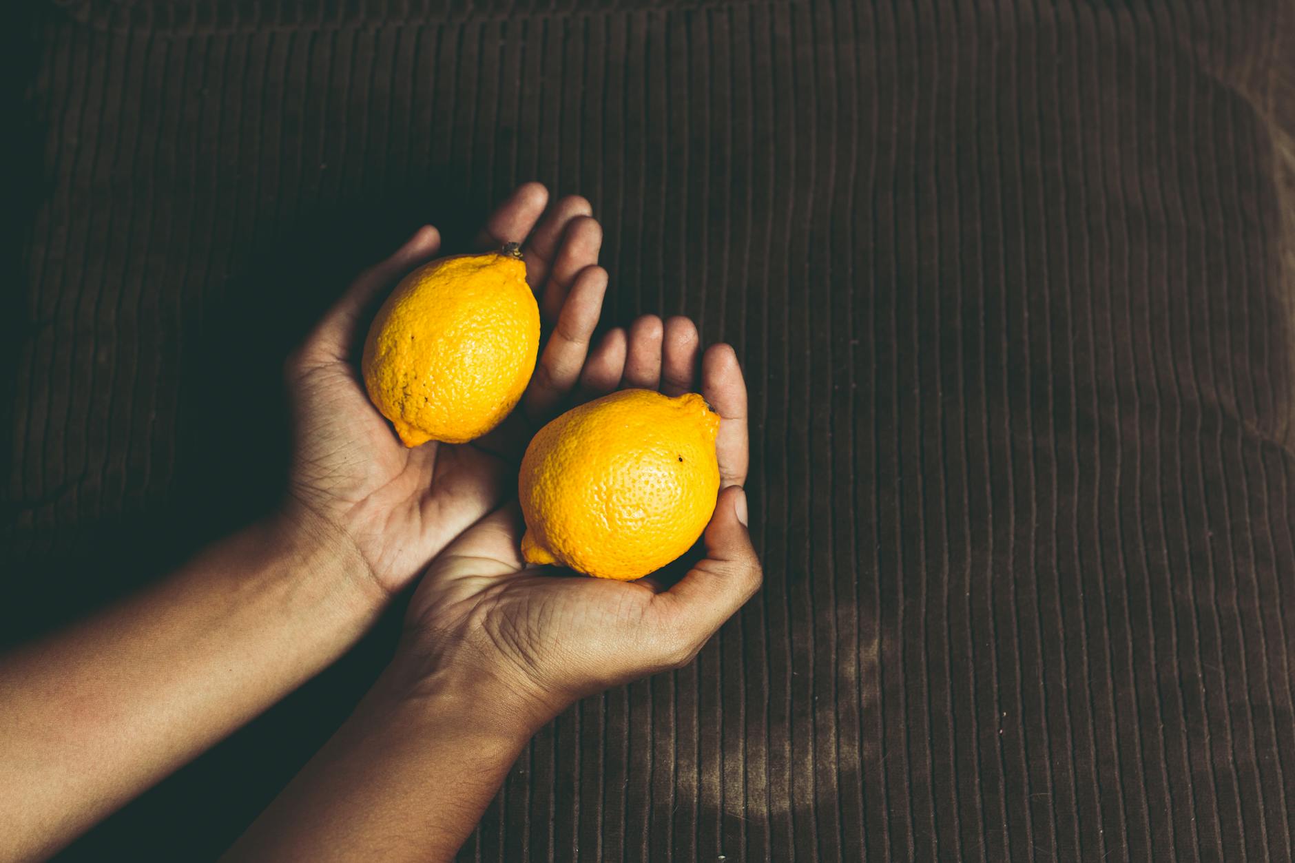 Two fresh lemons held in cupped hands, representing renewal and natural sensation